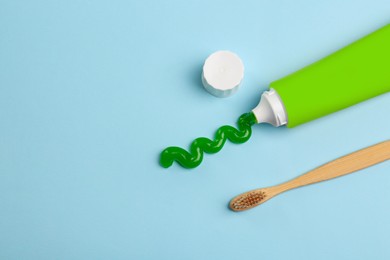 Photo of Tube of aloe toothpaste and toothbrush on light blue background, flat lay. Space for text