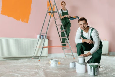 Photo of Professional decorators painting wall indoors. Home repair service