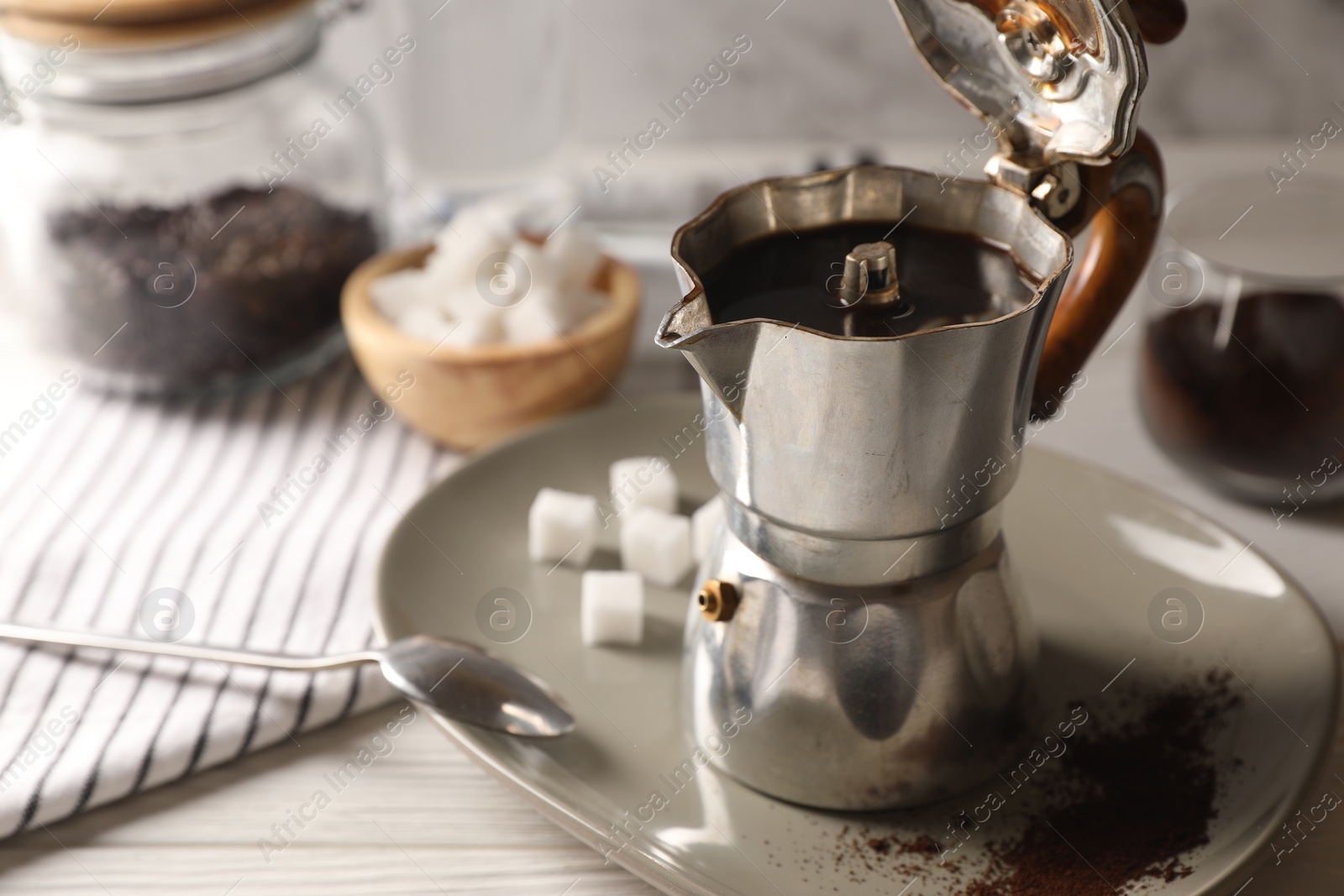 Photo of Brewed coffee in moka pot on white wooden table. Space for text