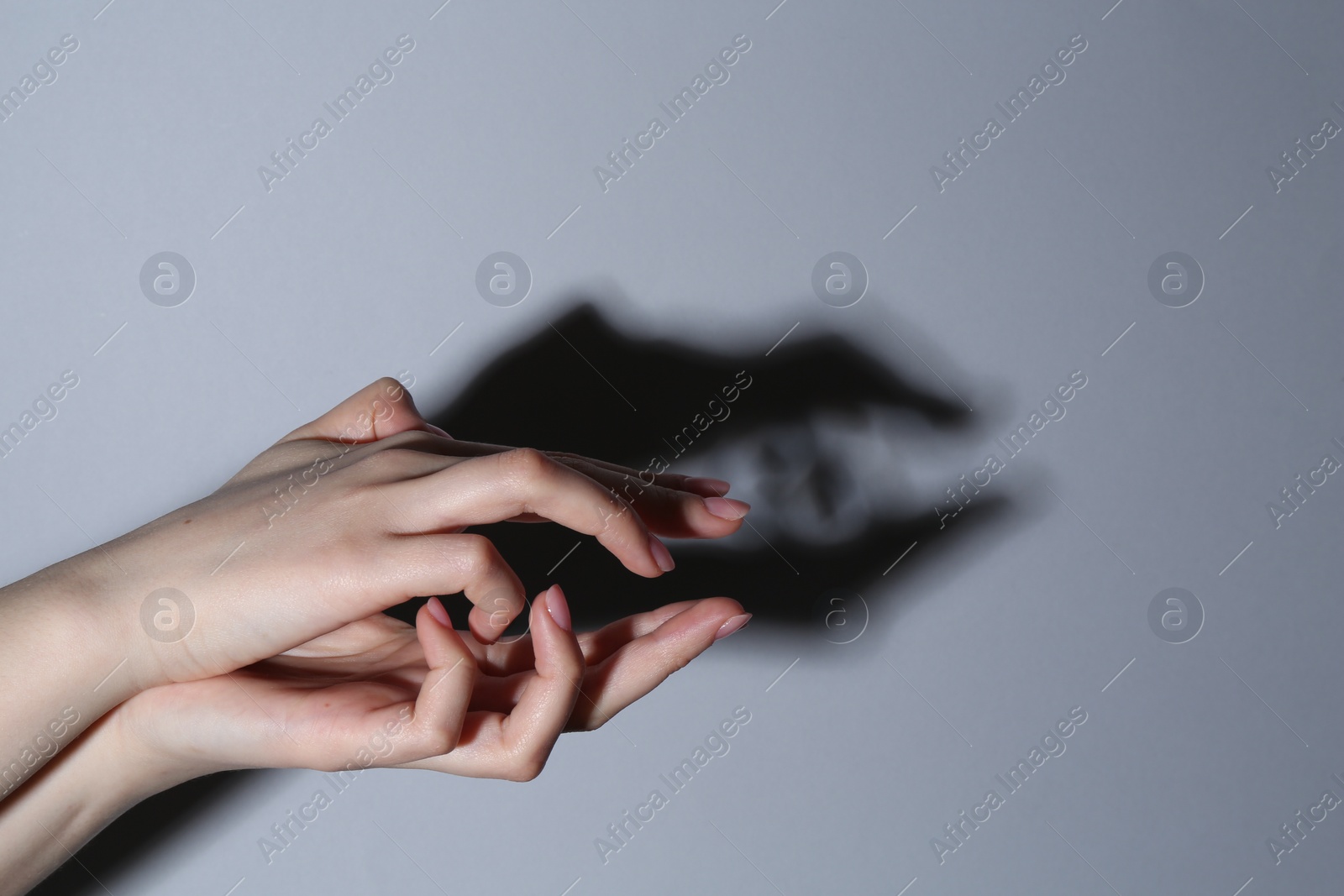 Photo of Shadow puppet. Woman making hand gesture like crocodile on grey background, closeup