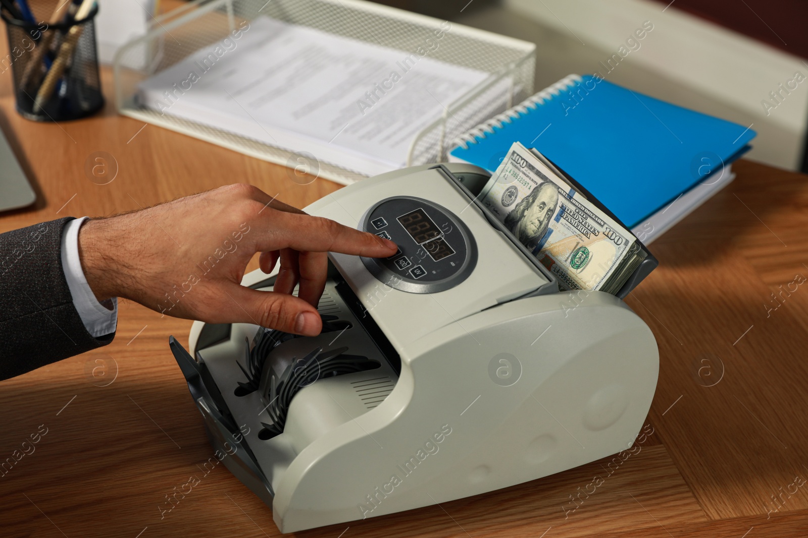 Photo of Man using banknote counter at wooden table, closeup