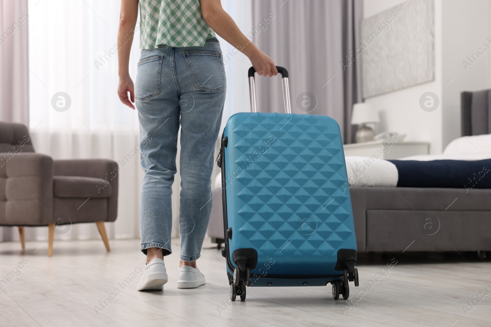 Photo of Guest with suitcase walking in hotel room, closeup