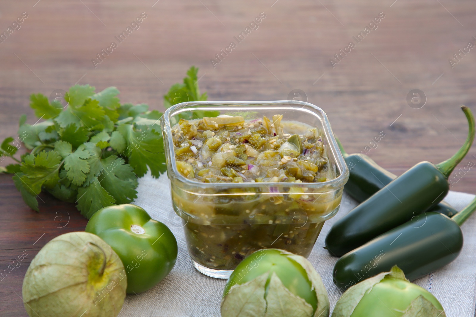 Photo of Tasty salsa sauce and ingredients on wooden table