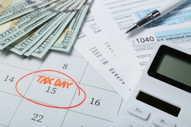 Calendar with date reminder about tax day, documents, pen, calculator and money, closeup