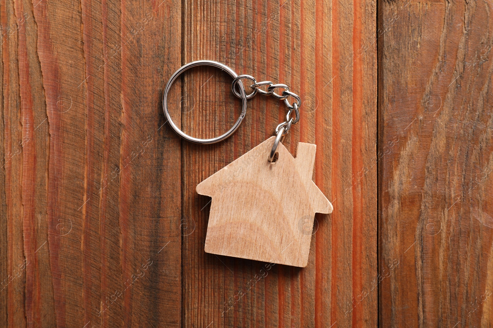 Photo of One keychain in shape of house on wooden table, top view