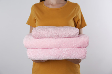 Woman holding fresh towels on light background, closeup