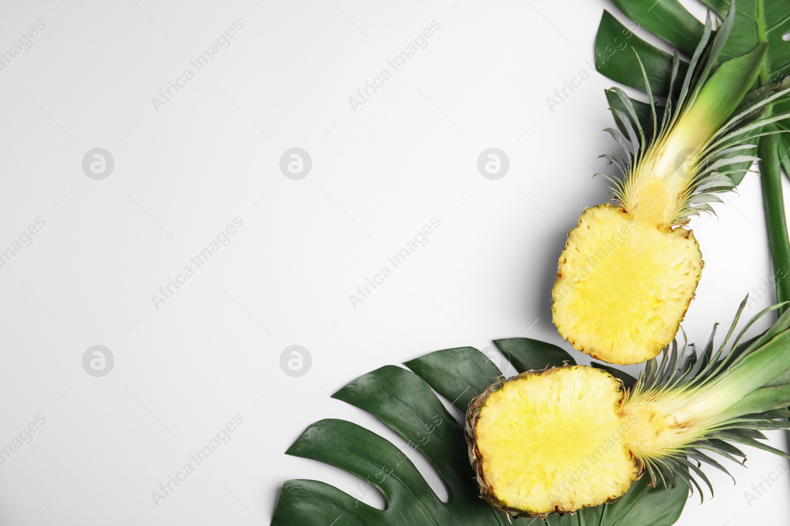 Photo of Halves of pineapple and palm leaves on white background, flat lay. Space for text