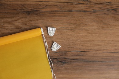 Stylish roller window blinds and details
on wooden table, flat lay. Space for text