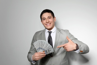 Photo of Portrait of young businessman with money fan on light background