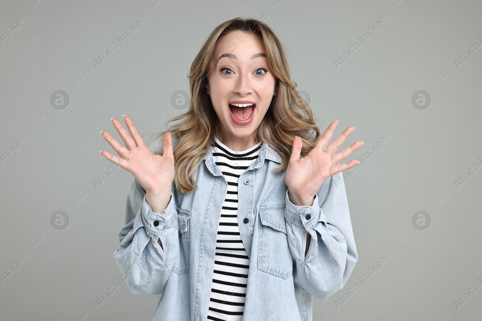 Photo of Portrait of happy surprised woman on grey background