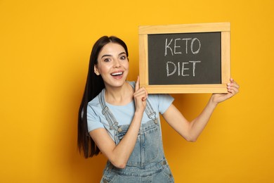 Emotional woman holding chalkboard with words Keto Diet on yellow background