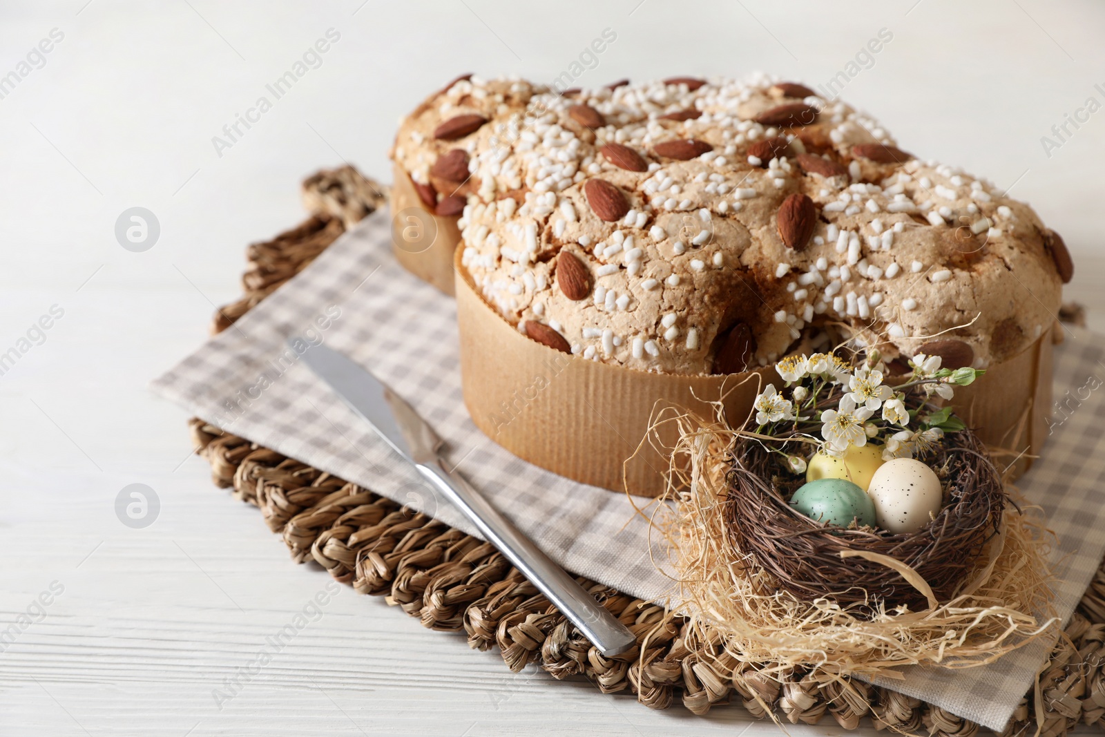 Photo of Delicious Italian Easter dove cake (Colomba di Pasqua) and decorative eggs on white wooden table