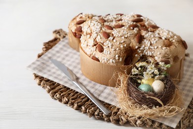 Photo of Delicious Italian Easter dove cake (Colomba di Pasqua) and decorative eggs on white wooden table