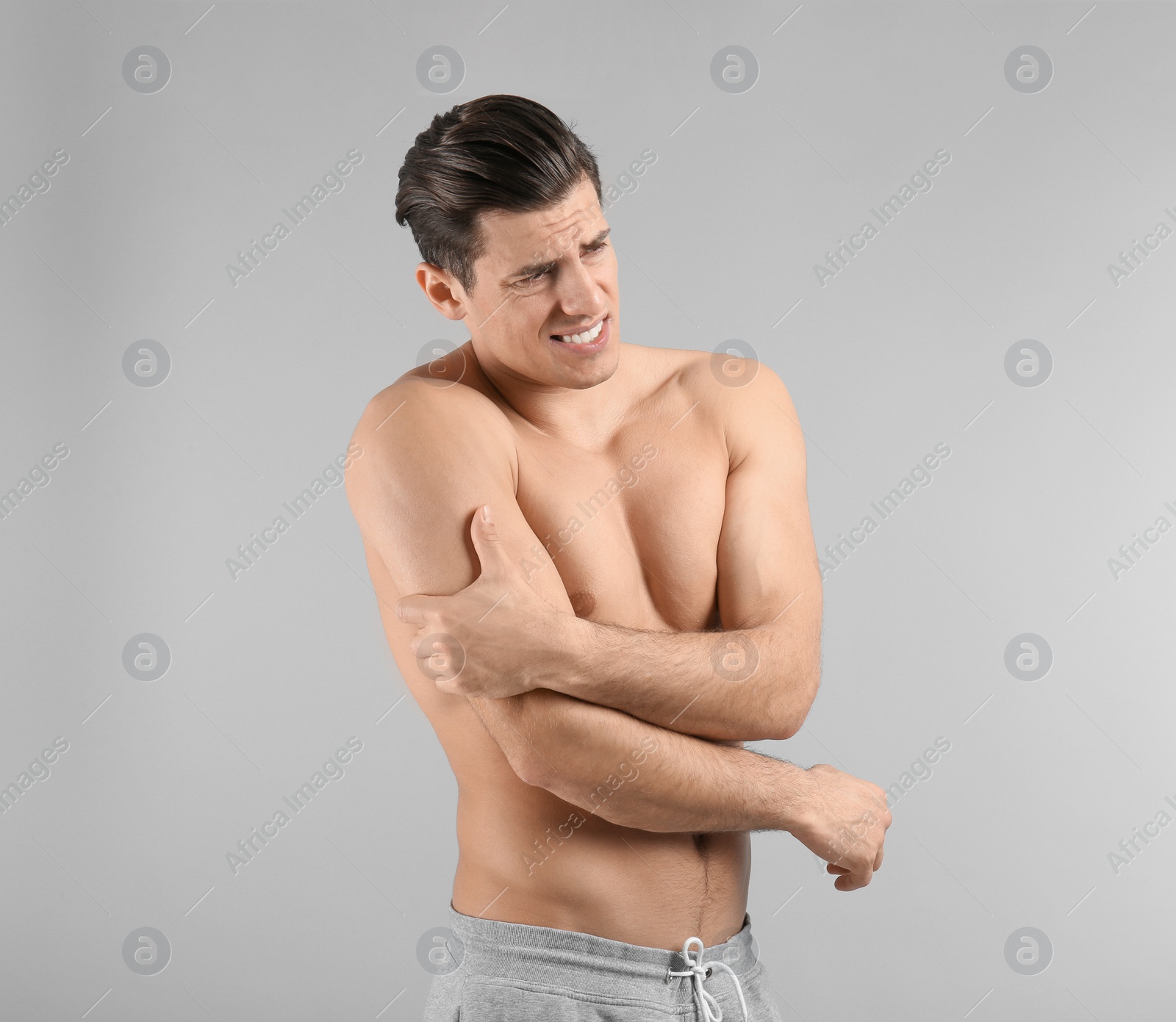 Photo of Young man suffering from pain in arm on grey background