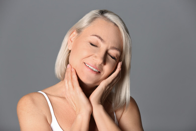 Portrait of beautiful mature woman on grey background