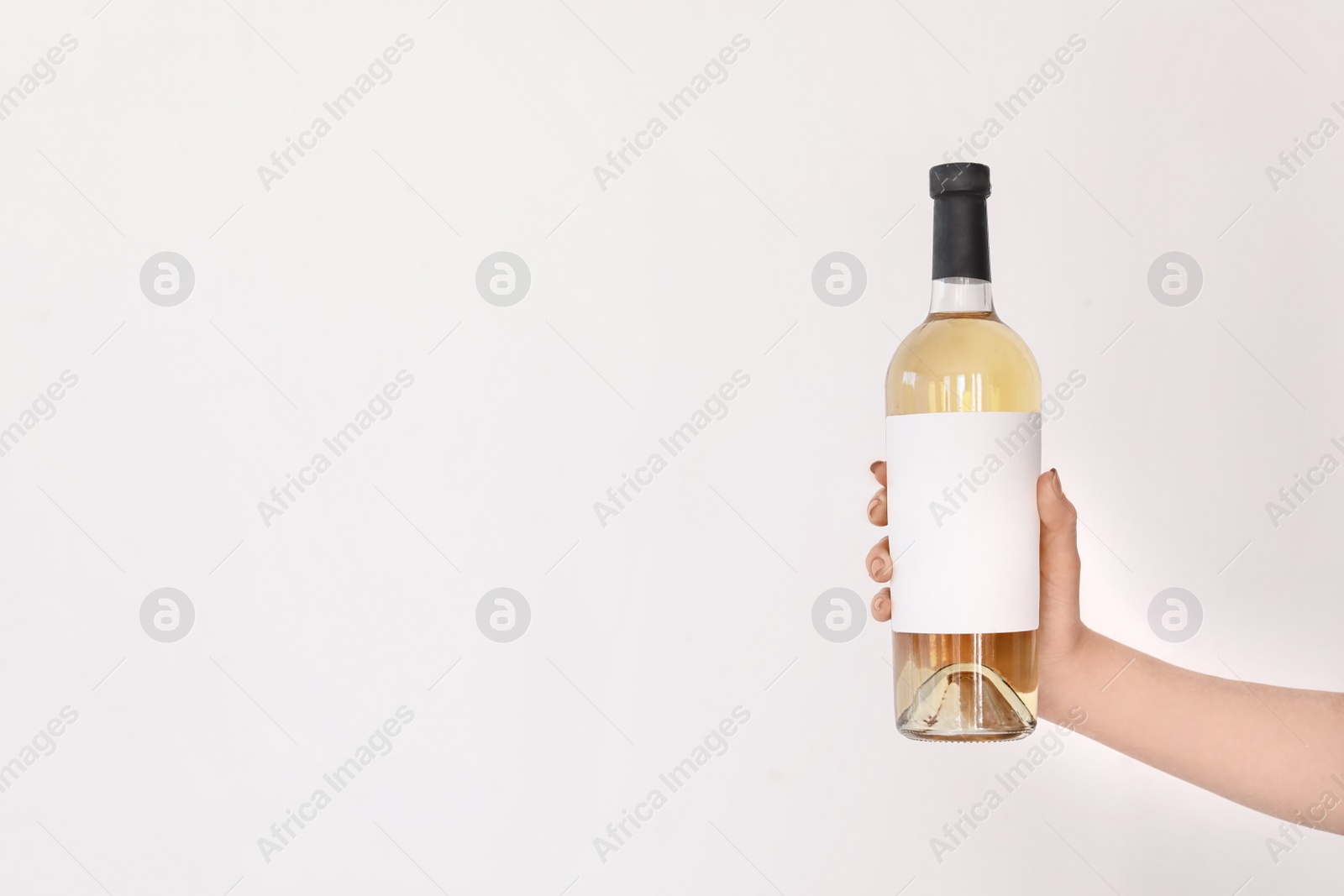 Photo of Woman holding bottle of wine on light background