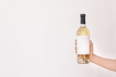 Photo of Woman holding bottle of wine on light background