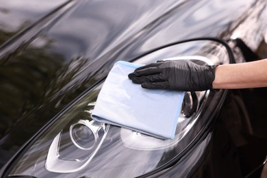 Photo of Woman wiping her modern car with rag, closeup