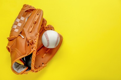 Photo of Catcher's mitt and baseball ball on yellow background, top view with space for text. Sports game