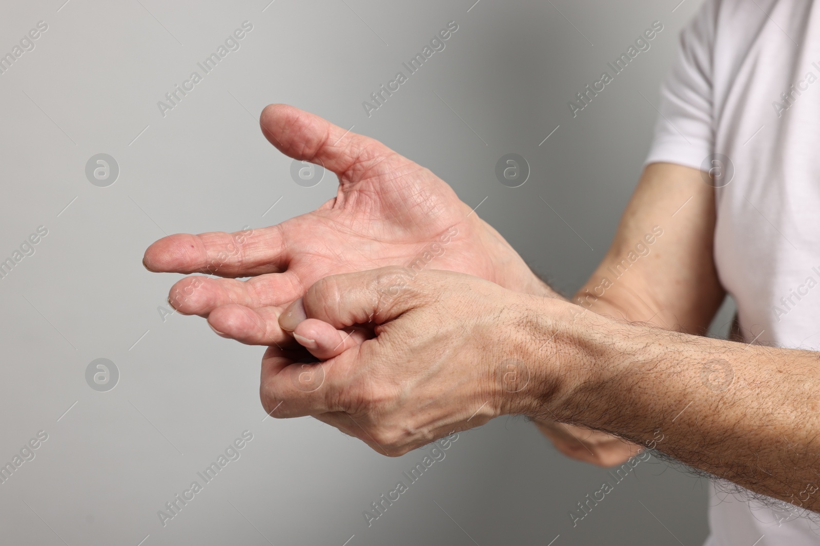 Photo of Arthritis symptoms. Man suffering from pain in hand on gray background, closeup