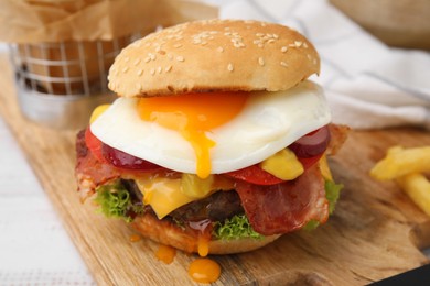 Photo of Delicious burger with fried egg on white wooden table, closeup