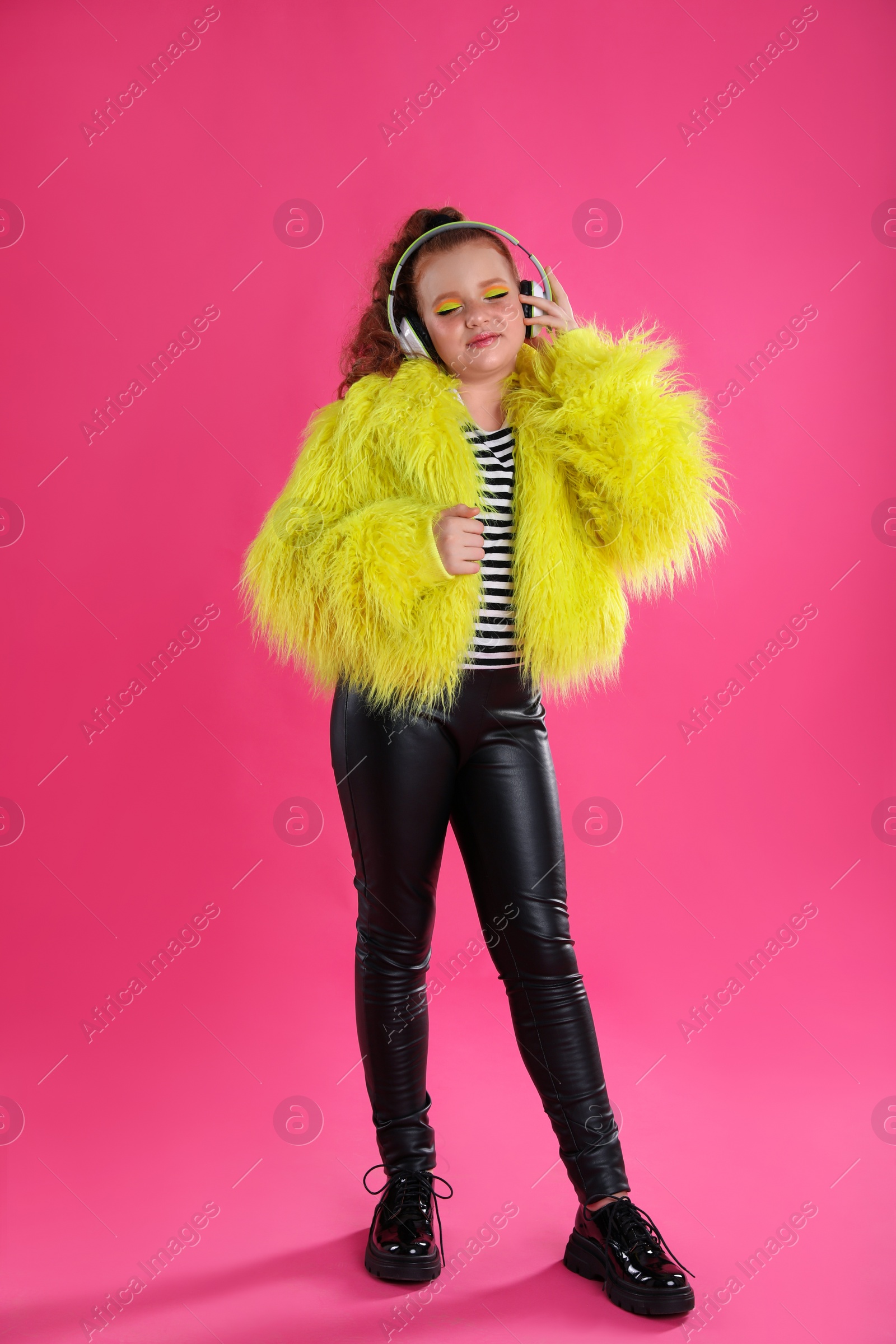 Photo of Cute indie girl with headphones on pink background