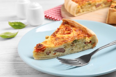 Photo of Delicious homemade vegetable quiche and fork on white wooden table, closeup