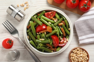 Photo of Delicious salad with green beans, mushrooms, pine nuts and tomatoes served on white wooden table, flat lay