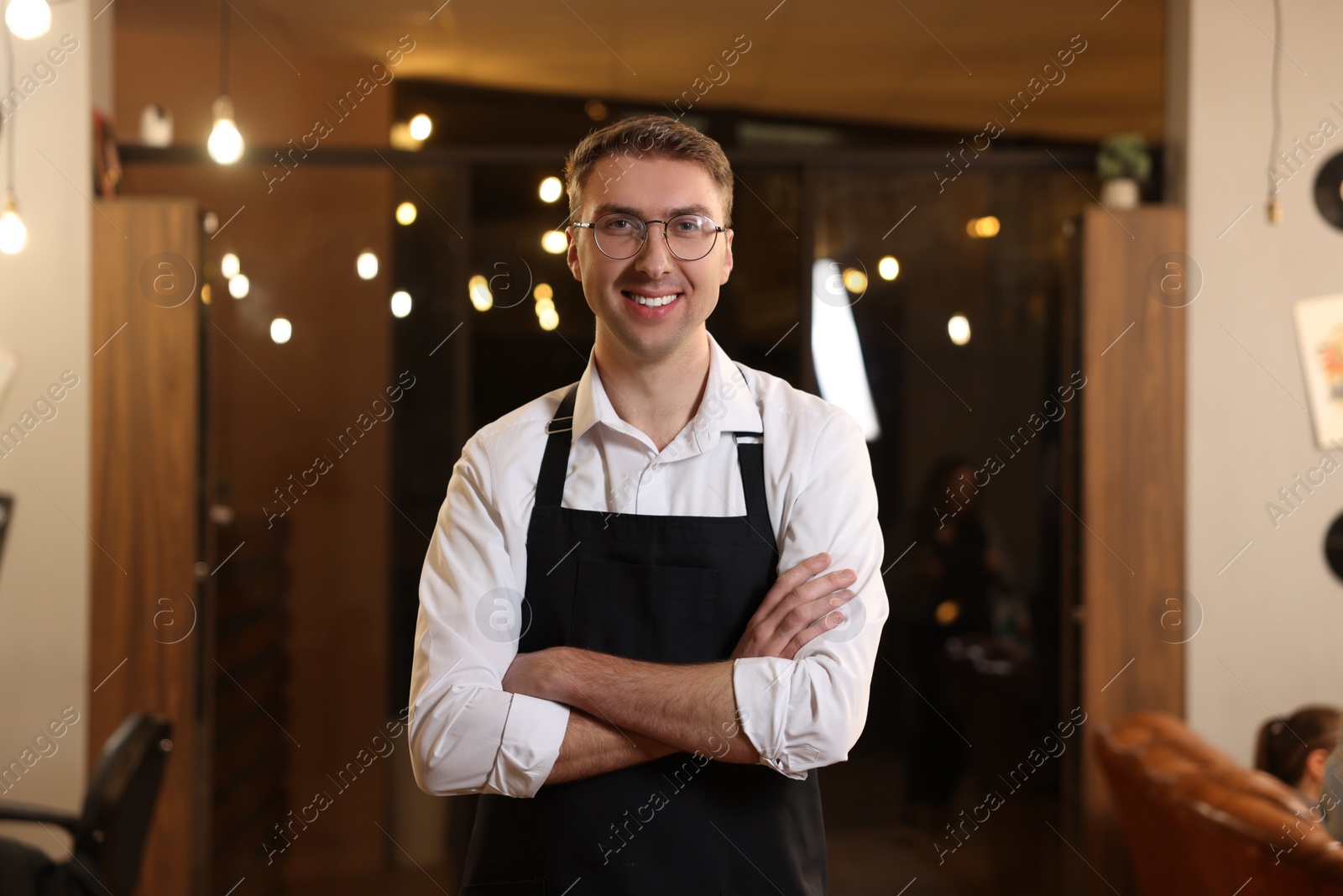 Photo of Portrait of professional hairdresser wearing apron in beauty salon