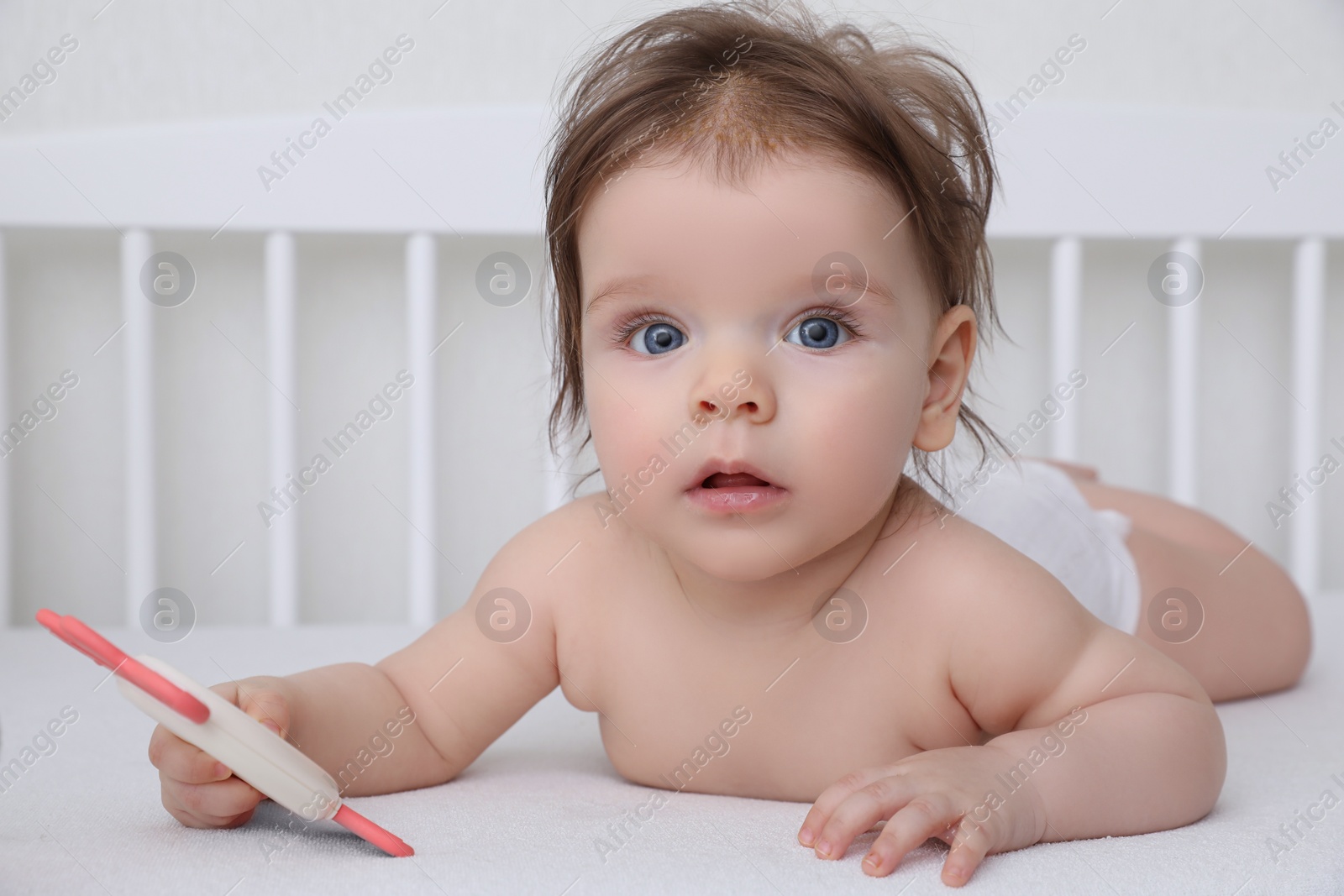 Photo of Cute little baby with teether in comfortable crib at home