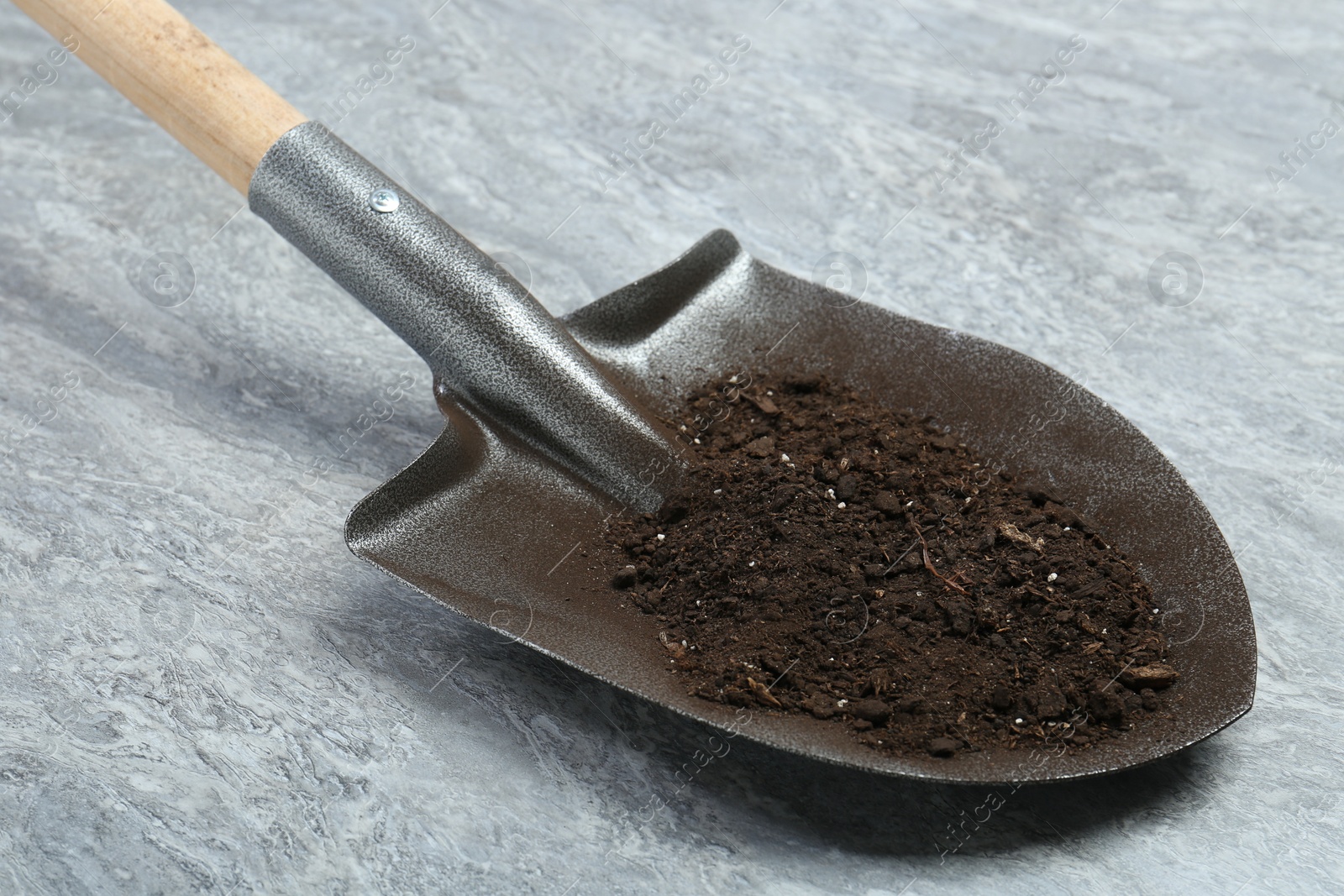 Metal shovel with fertile soil on gray textured surface Photo of Metal shovel with fertile soil on gray textured surface