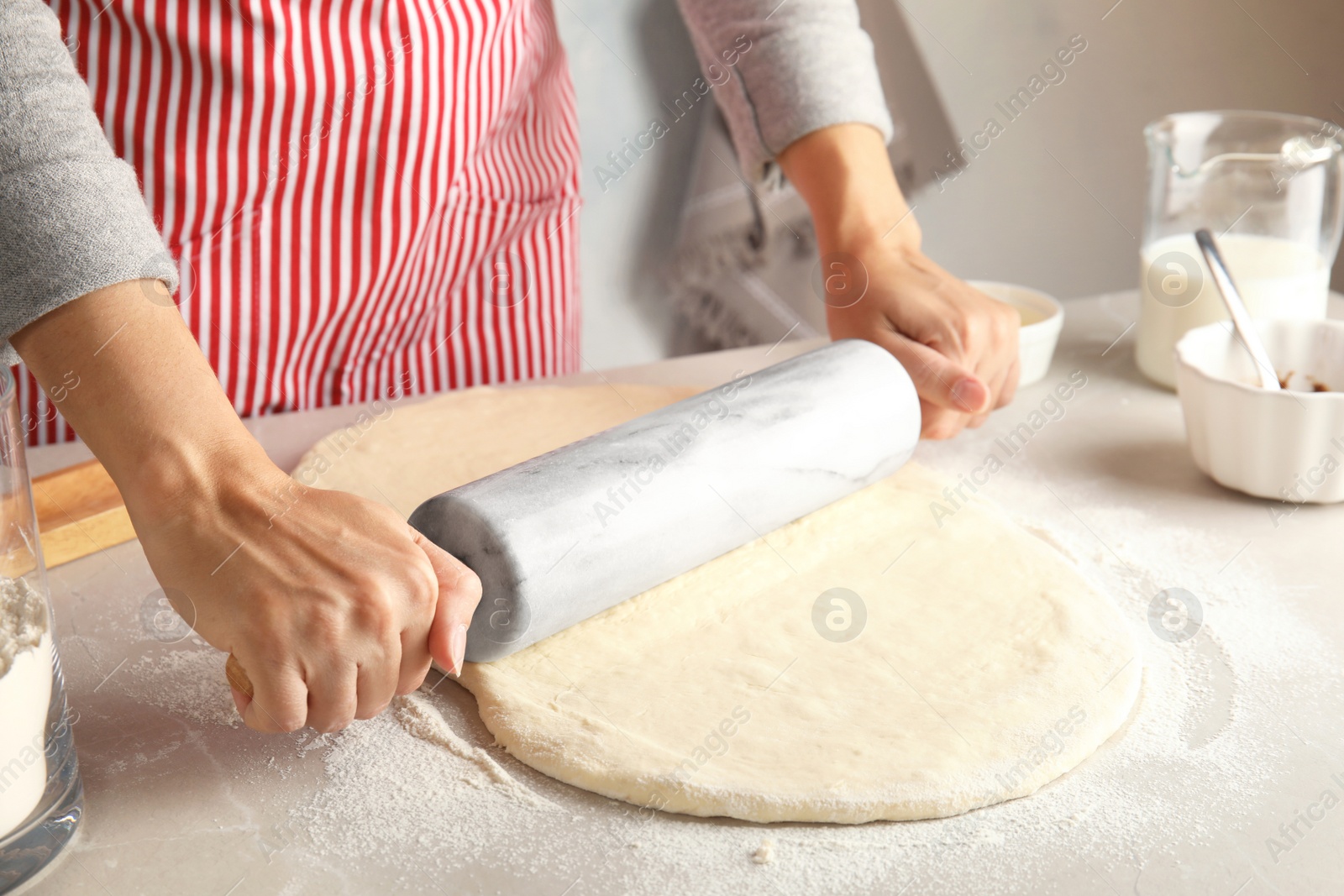 Photo of Woman rolling dough for cinnamon rolls on table, closeup