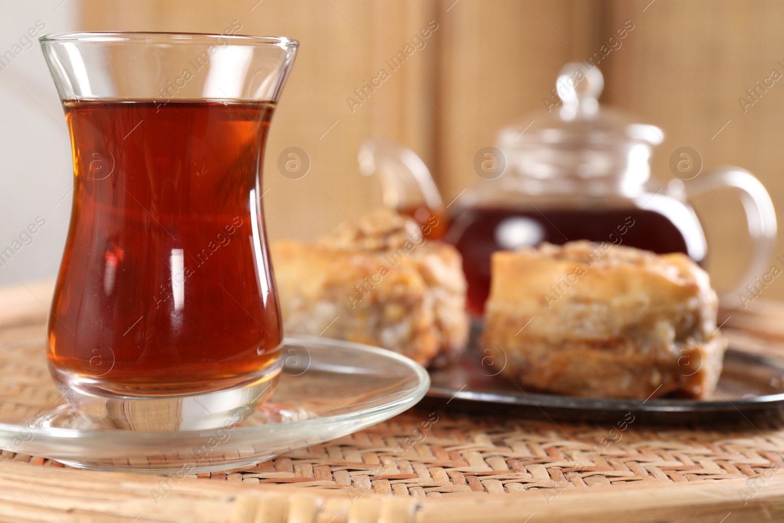 Photo of Traditional Turkish tea in glass on wicker table, closeup. Space for text