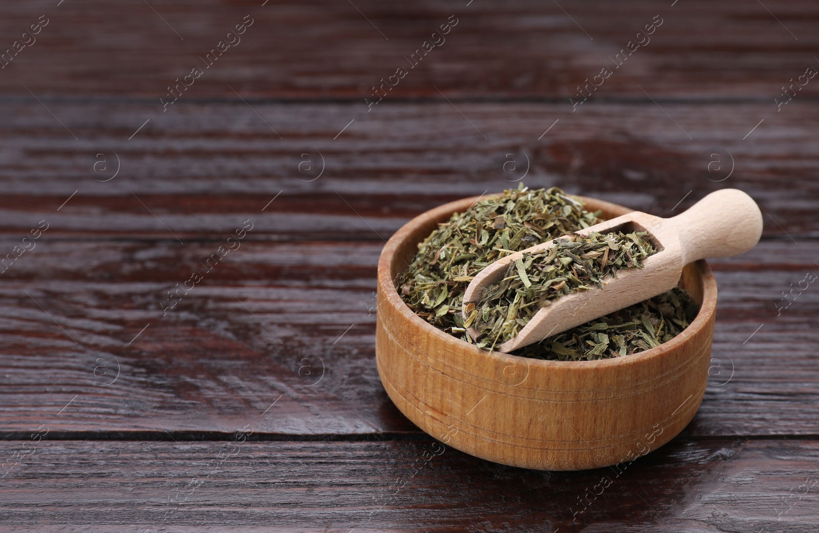 Photo of Bowl of dry tarragon and scoop on wooden table, space for text