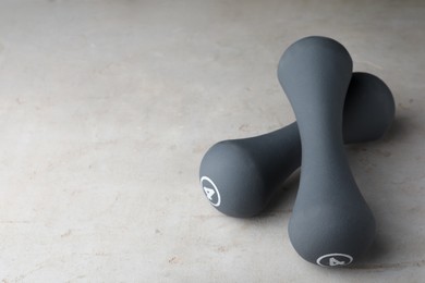 Photo of Grey rubber coated dumbbells on light table. Space for text