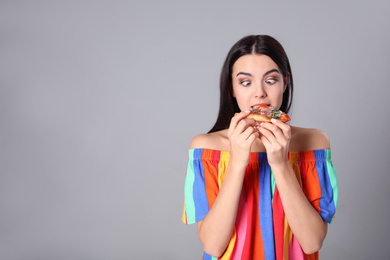 Photo of Funny woman eating pizza on grey background, space for text