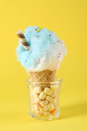 Photo of Sweet cotton candy in waffle cone on yellow background