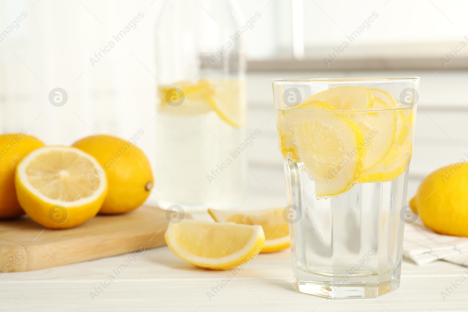 Photo of Soda water with lemon slices and fresh fruits on white wooden table in kitchen. Space for text