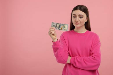 Sad woman with dollar banknote on pink background