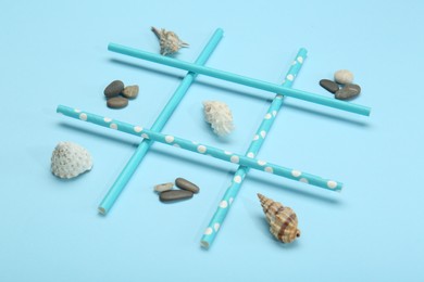 Photo of Tic tac toe game made with sea treasures on light blue background