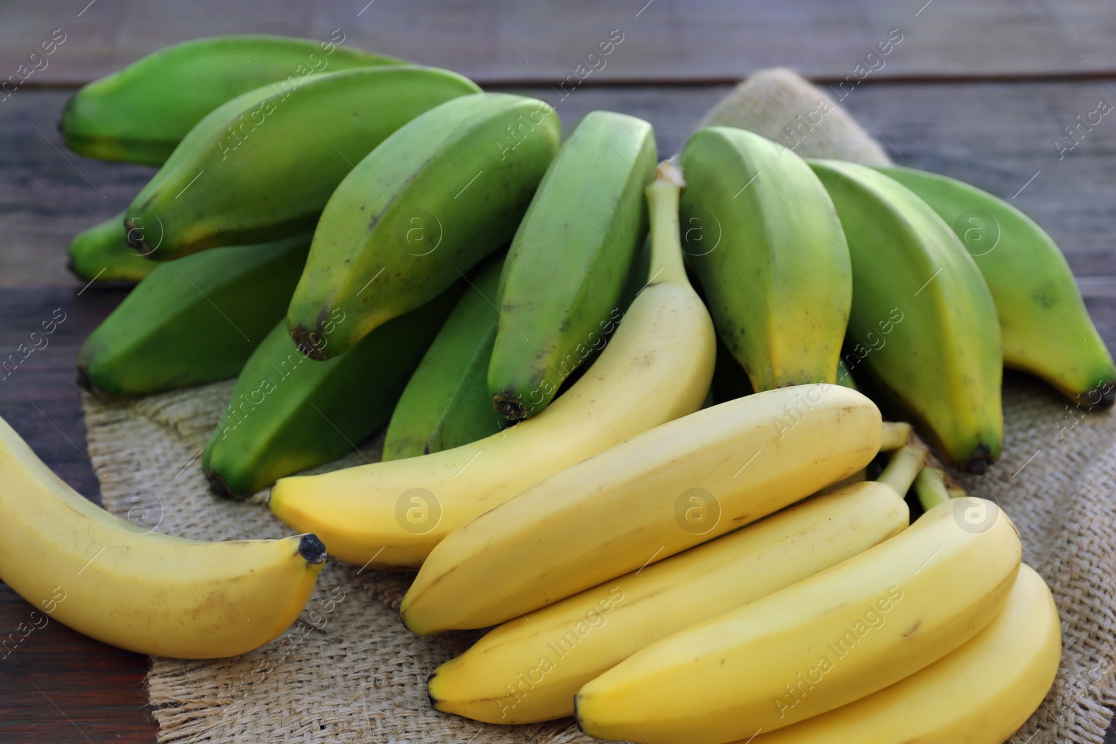 Photo of Different sorts of bananas on wooden table, closeup