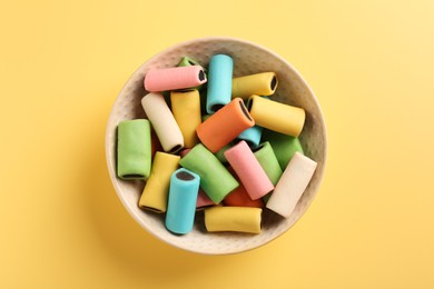 Photo of Bowl of tasty liquorice candies on yellow background, top view