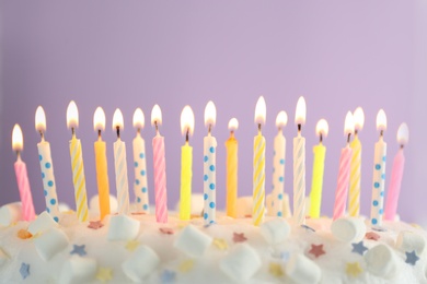 Photo of Birthday cake with burning candles on violet background, closeup