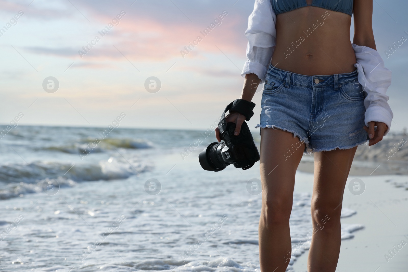 Photo of Photographer with professional camera near sea, closeup