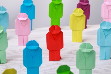 Photo of Many colorful paper figures on white wooden table. Recruiter searching employee