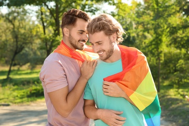 Photo of Happy gay couple with rainbow flag outdoors