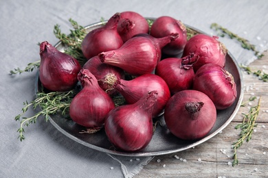 Plate with ripe red onions on table