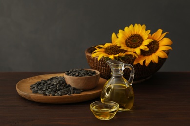 Sunflower oil and seeds on wooden table against grey background