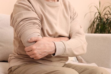 Senior man suffering from pain in his hand at home, closeup. Arthritis symptoms