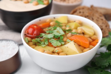 Photo of Tasty chickpea soup in bowls on white table, closeup